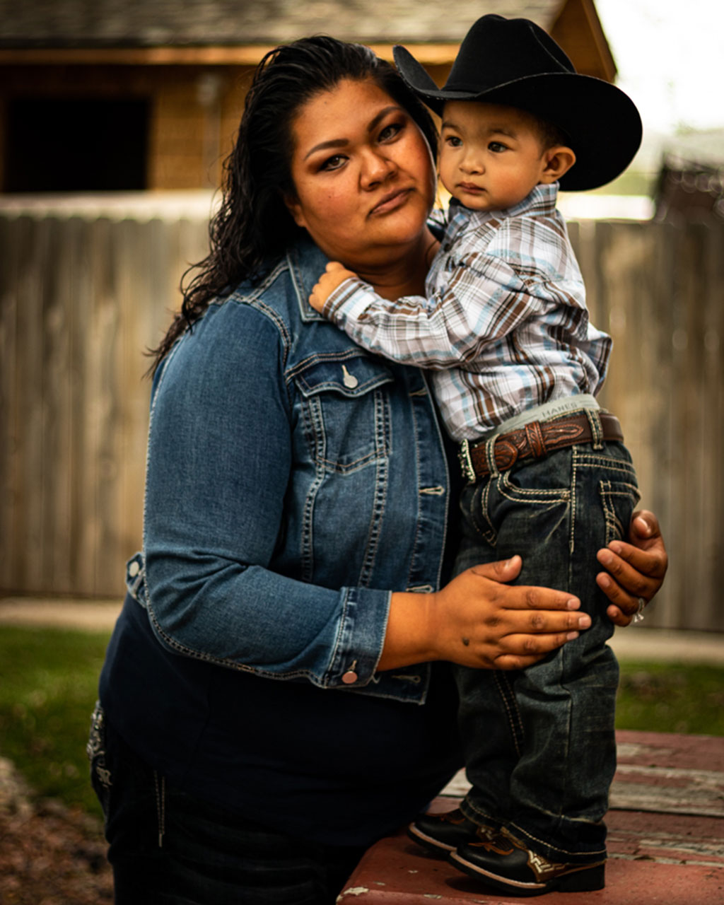 A mother holds her toddler aged son in a loving embrace.